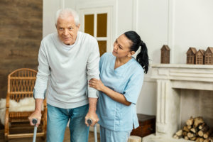 caregiver assisting elder man to walk